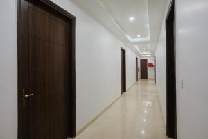 um corredor com portas pretas e paredes brancas em Super Townhouse 1291 Akshay Hotel em Gurgaon