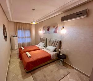 1 Schlafzimmer mit 2 Betten und orangefarbener Bettwäsche in der Unterkunft Maarif Cosy 4 lits Parking wifi Netflix Gratuit in Casablanca