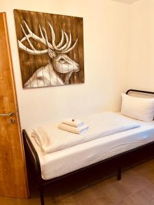 Bett mit einem Bild eines Hirsches an der Wand in der Unterkunft Apartments Maxim in Rust