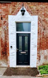 a black door on a brick building with a light at Purbeck Lodge in Swanage