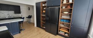 a kitchen with a black refrigerator and wooden shelves at Purbeck Lodge in Swanage