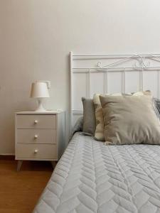 a white bed with a white dresser and a lamp at Castle House Xativa in Xàtiva