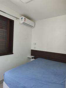 a bedroom with a blue bed and a window at Apartamento frente ao mar condomínio Jubiabá ilhéus olivença in Olivença