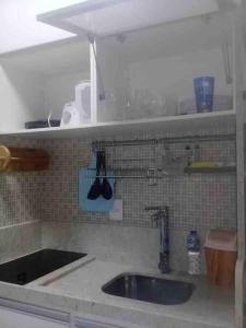 a kitchen with a sink and a tiled wall at Apartamento frente ao mar condomínio Jubiabá ilhéus olivença in Olivença