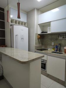 a kitchen with white cabinets and a white refrigerator at Apartamento frente ao mar condomínio Jubiabá ilhéus olivença in Olivença