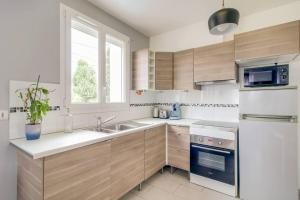 eine weiße Küche mit einer Spüle und einem Kühlschrank in der Unterkunft *Au Bord du Canal*Entre Paris et Disneyland in Chelles