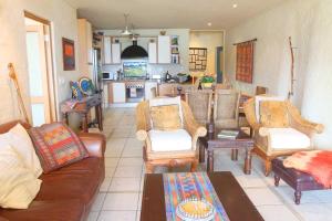 a living room with a couch and chairs and a kitchen at On the Beach in Hout Bay
