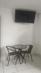 mesa con 2 sillas y TV en la pared en HOSPEDAJE BLESS, en Trujillo