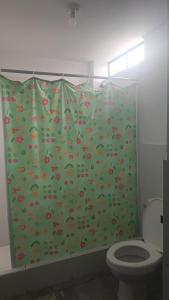 a bathroom with a green shower curtain with a toilet at HOSPEDAJE BLESS in Trujillo