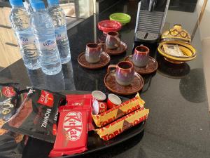 einen Tisch mit Tassen und Teller mit Essen und Wasser in der Unterkunft Maarif Cosy 4 lits Parking wifi Netflix Gratuit in Casablanca