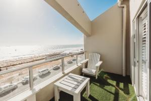 a balcony with a chair and a view of the beach at Voir la Mer - Blouberg Beach in Bloubergstrand