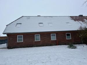 a red brick house with a snow covered roof at Schildetal Apartment's in Vellahn