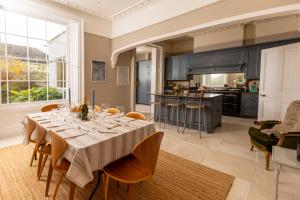 a dining room with a table and a kitchen at Pittville House in Cheltenham