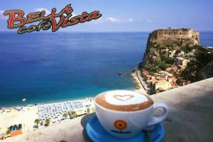 Una taza de café sentada en una cornisa con vistas a la playa en B&B Omnia Scilla en Scilla