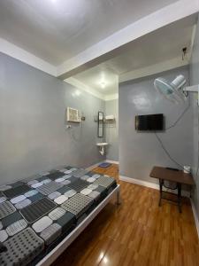 um quarto com uma cama num quarto com uma televisão em Maicaellas Transient Room em Coron
