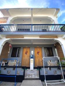 a house with two wooden doors and a balcony at Maicaellas Transient Room in Coron