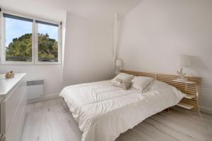 - une chambre blanche avec un lit et une fenêtre dans l'établissement Ecrin de tranquillite en plein coeur de la Baule, à La Baule