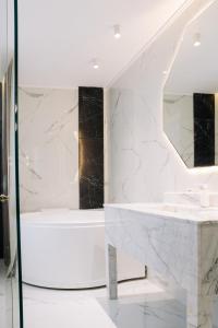 a bathroom with a tub and a sink and a mirror at Luxurious Mamu Apartment in Batumi