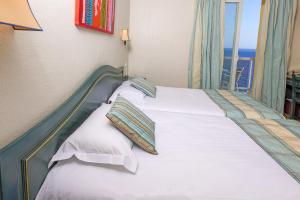 a bed with white sheets and pillows in a room at Hotel Saint Christophe in Calvi