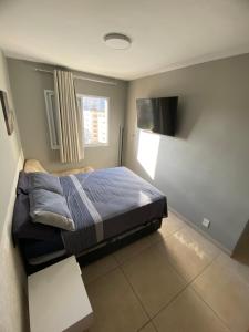 a bedroom with a bed and a flat screen tv at ! PRAIA DA ENSEADA GUARUJÁ Churrasqueira GOURMET ! in Guarujá