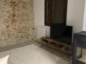 - un salon avec une télévision et un mur en pierre dans l'établissement Casa en Vilanova de Meià, à Vilanova de Meyá