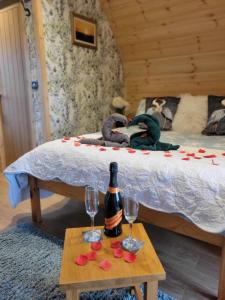 Beautiful Glamping Pod with Central Heating, Hot Tub, Garden, Balcony & views - close to Cairnryan - The Herons Nest by GBG في Glenluce: غرفة نوم مع سرير وزجاجة من النبيذ وطاولة