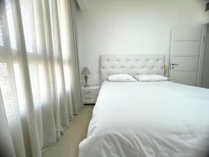 een witte slaapkamer met een bed en een raam bij LOVELY 2BR GOLF RESIDENCE EILAT in Eilat