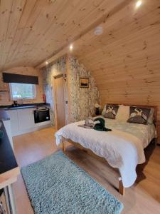 - une chambre avec un lit dans une cabane en rondins dans l'établissement Beautiful Glamping Pod with Central Heating, Hot Tub, Garden, Balcony & views - close to Cairnryan - The Herons Nest by GBG, à Glenluce