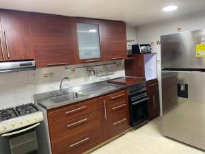 uma cozinha com armários de madeira e um frigorífico de aço inoxidável em Casa 30 em Bogotá