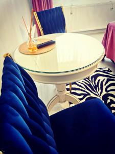 einen weißen Tisch und zwei blaue Stühle mit Fernbedienung in der Unterkunft Studio Alexandra in Galaţi