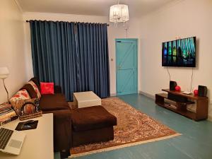 a living room with a brown couch and a blue door at Graceland 2 in Nakuru