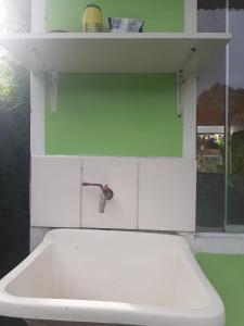 un fregadero blanco con un grifo en una pared verde en Cabañitas Shollet, en Oxapampa