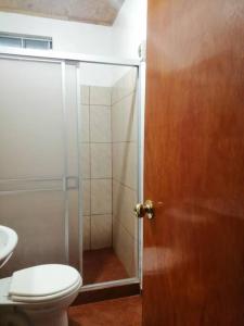 a bathroom with a toilet and a glass shower door at Cabañitas Shollet in Oxapampa