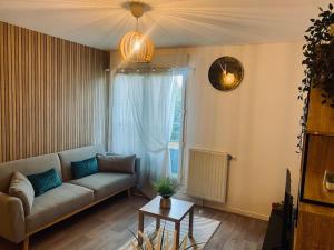 sala de estar con sofá y reloj en la pared en Charmant T2 moderne /proximité CDG / Confort, en Villepinte