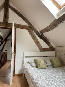 a bedroom with a white bed and wooden ceilings at Le Fauverney in Fauverney