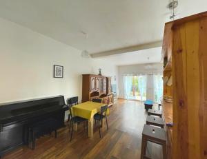 uma sala de estar com um piano, uma mesa e cadeiras em 9 min from Paris&Orly - House with terrace/garden em Arcueil