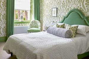 Schlafzimmer mit einem großen Bett mit einem grünen Kopfteil in der Unterkunft Leonardslee House at Leonardslee Lakes & Gardens in Horsham