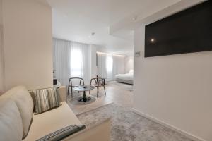 AKOYA HOTEL في إيلات: غرفة معيشة مع أريكة وتلفزيون على الحائط