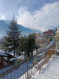 a fence in the snow with a tree and mountains at Terrace Home in Saint Vincent