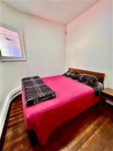 Schlafzimmer mit einem Bett mit roter Bettwäsche und einem Fenster in der Unterkunft Viva Chile Providencia - Bustamante in Santiago