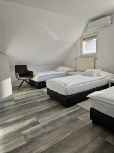 um quarto com três camas e uma cadeira em Nefelejcs Vendégház em Gödöllő
