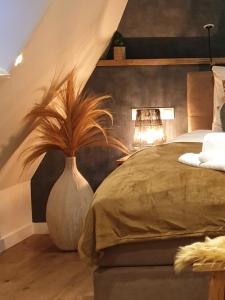 a bedroom with a bed and a vase with a plant at Suite De Brinkparel in De Koog