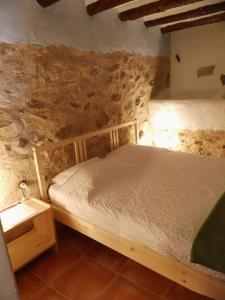 a bedroom with a bed in a stone wall at Guest House Guapas in La Garapacha