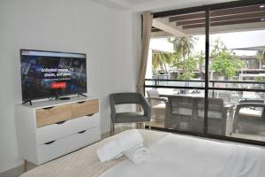 1 dormitorio con TV y 1 cama con silla en GL luxury apartment 203 Bay Point, en San Andrés