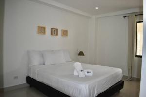 Un dormitorio blanco con una cama con una toalla. en GL luxury apartment 203 Bay Point, en San Andrés