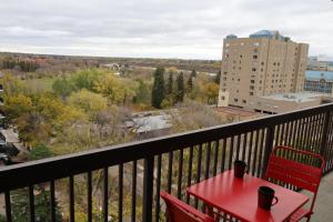 una mesa roja y 2 sillas en el balcón en Cambridge 2 BR king gym Near Uni RUH City H en Saskatoon