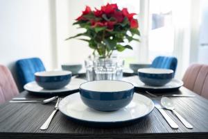 a table with blue and white plates and a vase with red flowers at Open Mind Property - 6 Luxury Bedrooms with Free Parking in Portsmouth