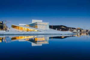 a building with a reflection in a body of water at Luxurable super central 3 BR apt for a family of 6 in Oslo in Oslo