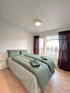 um quarto com uma cama com lençóis verdes e uma janela em Luxurable super central 3 BR apt for a family of 6 in Oslo em Oslo
