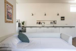 a white bedroom with a white bed and a kitchen at Il trilocale dell'Isola milanese in Milan